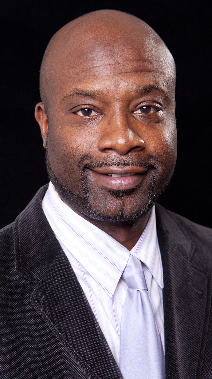 Headshot of a man wearing a gray jacket and light gray necktie.