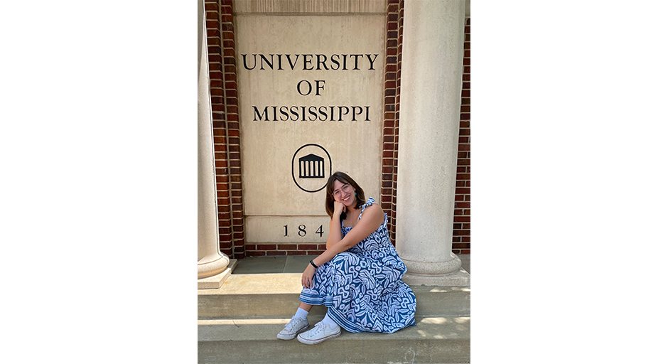 Sydney Rush takes a photo in front of an Ole Miss sign.