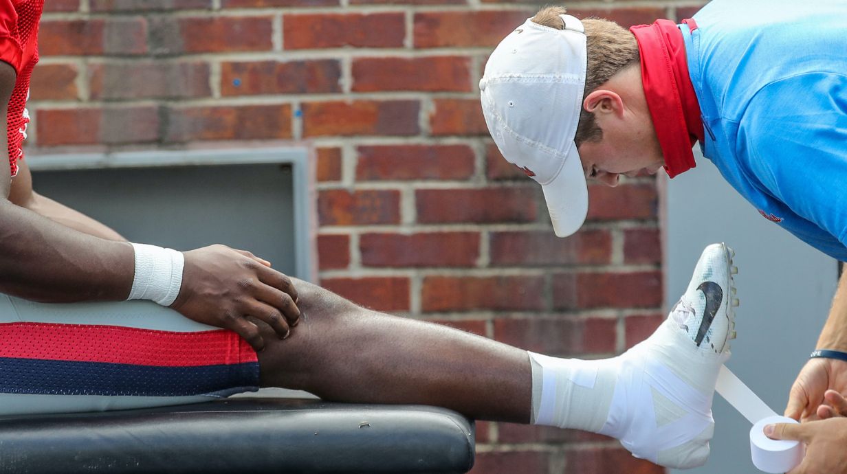 Student of the Master of Science and Athletic training wrapping a football players ankle.