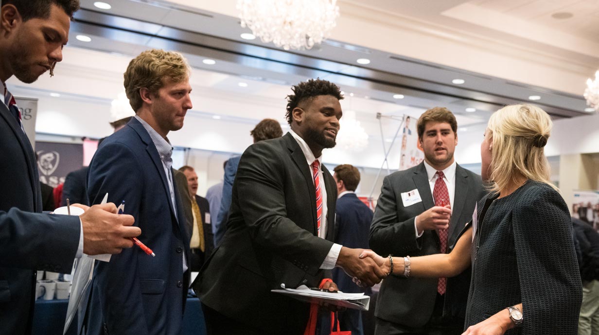  Student at a job fair shaking the hand of a woman. 