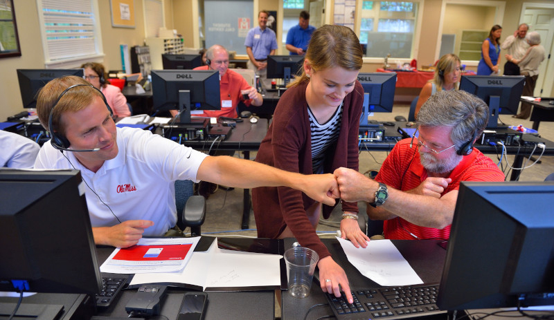 Dean Cyree doing a fist shake with another student. Third student looking on. 