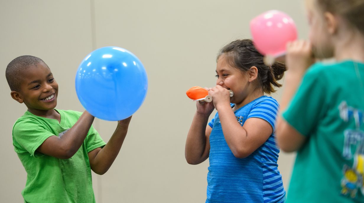 three students blowing up balloons