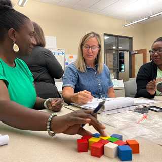 Student teachers use cubes to solve math problems.