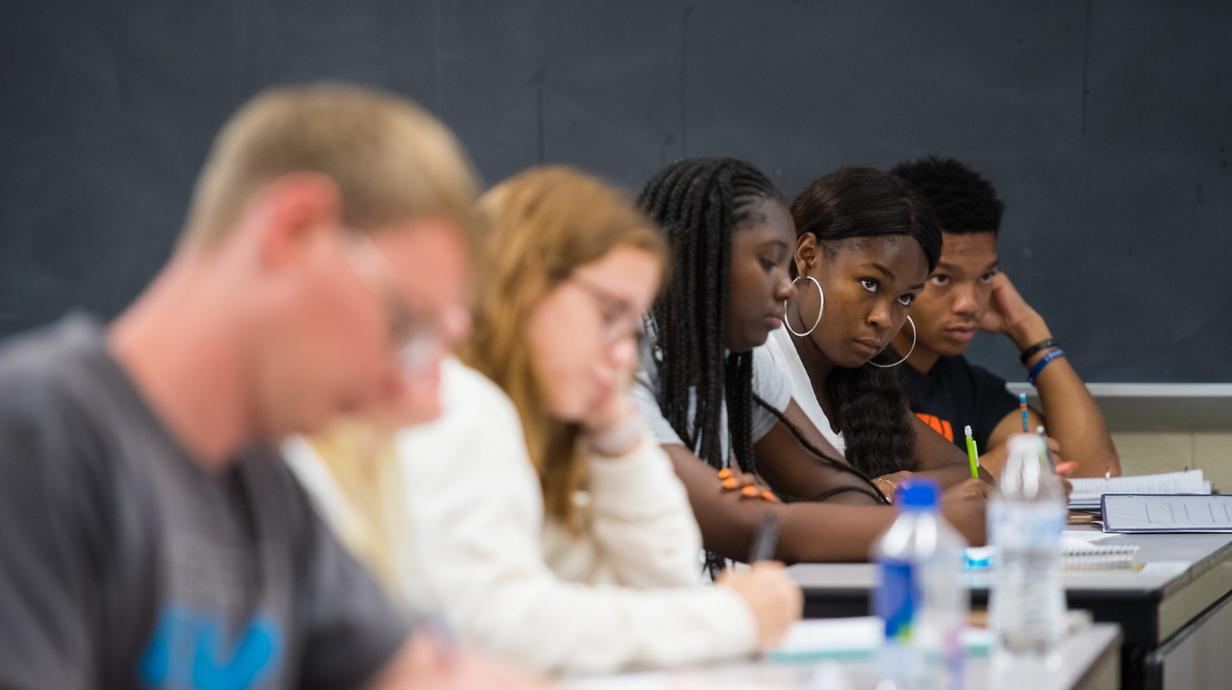 Doctor of Philosophy (Ph.D.) in Teacher Education - A row of 5 seated students look towards the instructor at the front of the classroom.