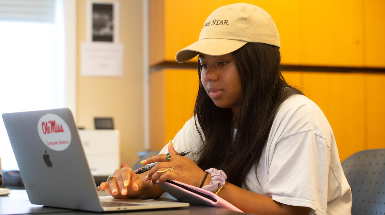 A student studies on her computer in a classroom