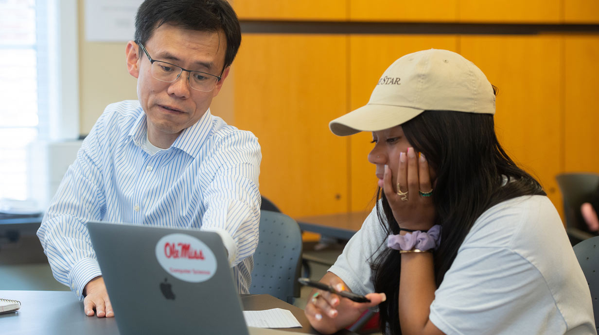 Professor and student sitting looking at laptop computer