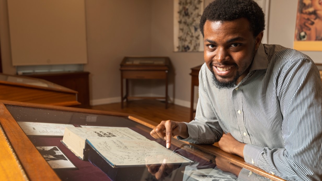 student pointing at an object in the glass case in the library archive 