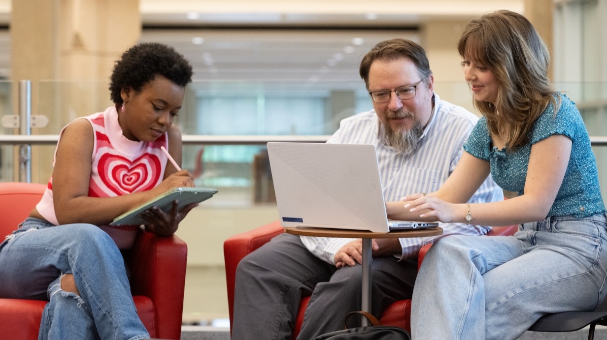 two students sitting and talking with Dr. Pfrenger in the Union