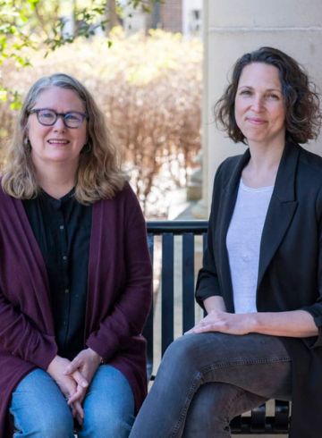 Dr. Ellis and Dr. Kreisel sit outside Bondurant Hall.