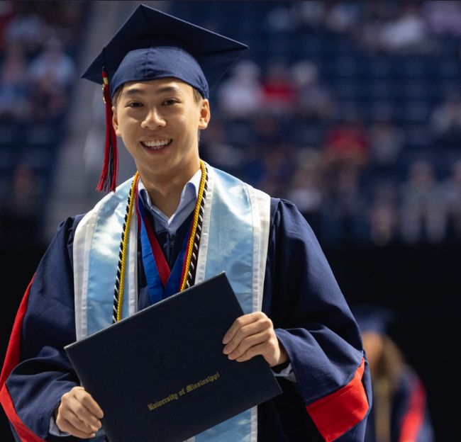 Student in regalia holding diploma