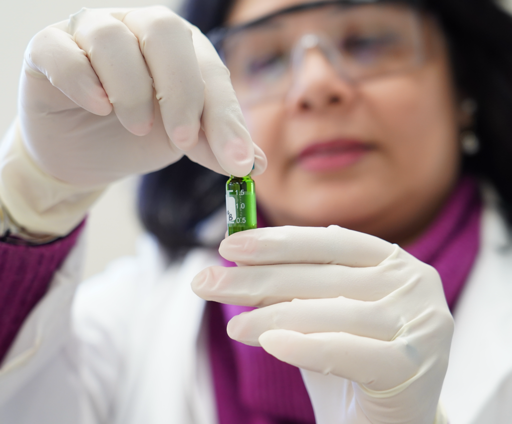 Scientist looking at chemical vial.