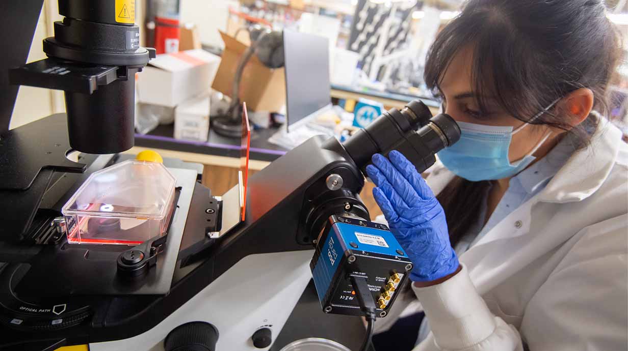 A lab worker uses a microscope in the biochemistry lab.