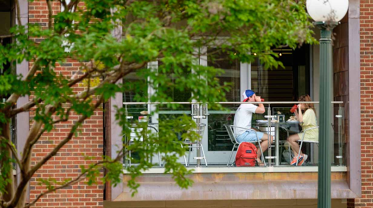 A pair of students enjoy dining on the balcony of Rebel Market.