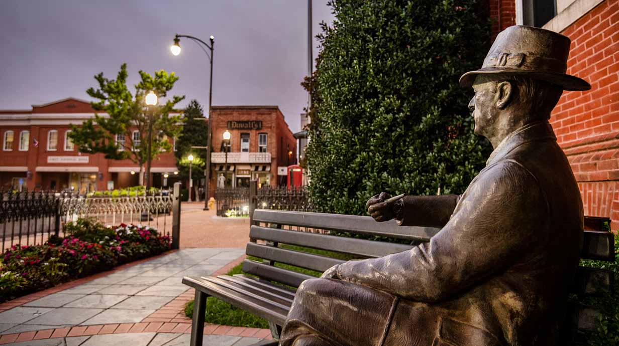 The statue of William Faulkner looks over the Oxford Square at sundown.