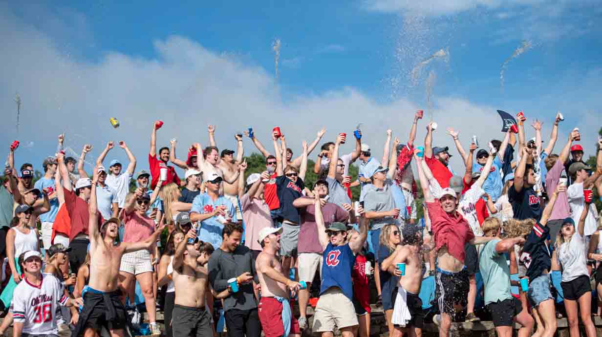 Ole Miss students in right field celebrate a Ole Miss home run by throwing their drinks in the air.